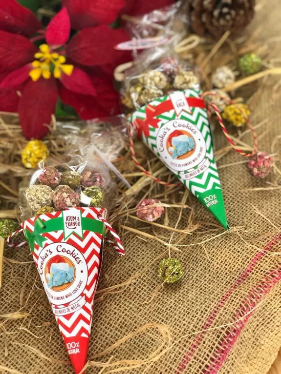 Natuerliche weihnachtliche Hundekekse in roten und gruene Snacktueten dekoriert mit Tannenzapfen und Weihnachtsdeko
